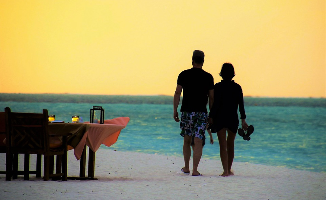 photo of couple walking on the beach