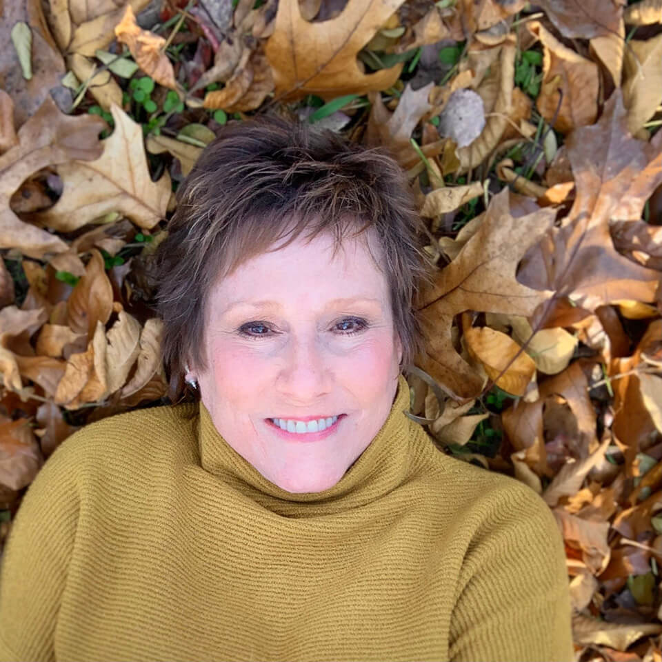 photo of Lisa Kipps-Brown lying in fall leaves